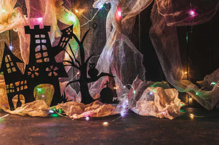 Witch's house with a grave and a scary tree cut out of black paper on a wooden wall with a cobweb. copy space. Crafts for halloween celebration concept. Handwork.の写真素材