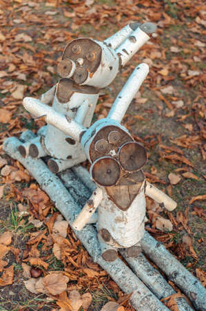 Wooden figurines of easter bunnies in a forest park on a background of dry leaves. Two rabbits made of birch bars and branches, decoration for Easter.の写真素材