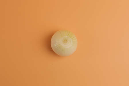 white onions in husks on a beige background, unpeeled sweet onions on the surface,onions in a minimalist style, vitamins, healthy eating concept. Top view. Copy space.の写真素材