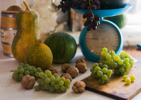 Autumn still life with pumpkins,walnuts,melons, watermelon and grapes on a scale to scale and on a wooden white table. Autumn harvest concept. Happy Thanksgiving. Selective focus. Template for design.の写真素材