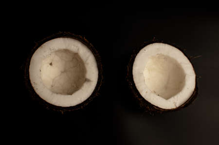 ugly organic coconut on a black background, isolate. a broken nut in a shell the white insides of a coconut, which began to decompose and covered with fungus and mold. Spoiled products.の写真素材