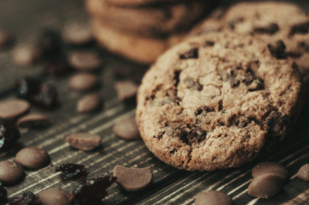 A stack of oatmeal cookies with chocolate pieces and candied fruits lies on a wooden table. Rustic...