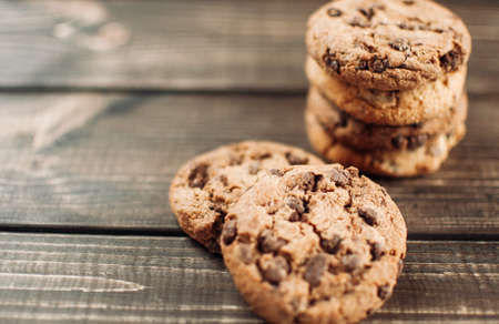 A stack of chocolate chip cookies lies on a wooden table. Rustic table. Vintage toning. Dietary useful cookies without gluten. Copy space.の写真素材