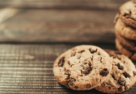 A stack of chocolate chip cookies lies on a wooden table. Rustic table. Vintage toning. Dietary...