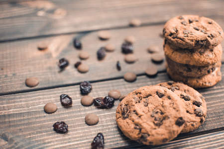 A stack of oatmeal cookies with chocolate pieces and candied fruits lies on a wooden table. Rustic table. Vintage toning. Dietary useful cookies without gluten. Copy space.の写真素材