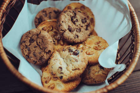 Cookies with chocolate lies in a wicker basket. A basket with gluten free cookies on a wooden table. Selective focus.の写真素材