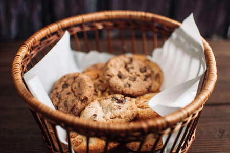 Cookies with chocolate lies in a wicker basket. A basket with gluten free cookies on a wooden table. Selective focus.の写真素材