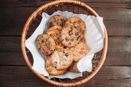 Cookies with chocolate lies in a wicker basket. A basket with gluten free cookies on a wooden table. Selective focus.の写真素材