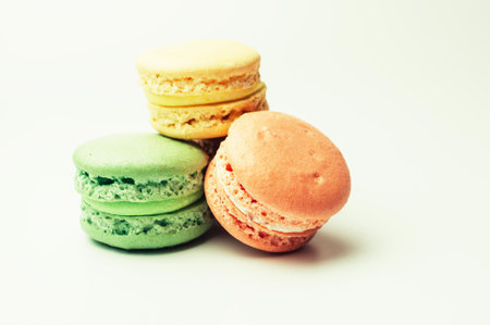 three fresh colored macaroons lie in a heap in the center. Meringue on an isolated background with copy spaceの写真素材