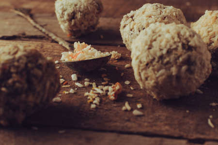 Healthy chocolate energy bites with nuts, dates, coconut flakes on a wooden table. Home made vegetarian gluten free healthy snacks. Vintage toning.の写真素材
