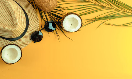 Summer composition. Tropical palm leaves, hat, glasses and broken coconut on a sandy background. The...