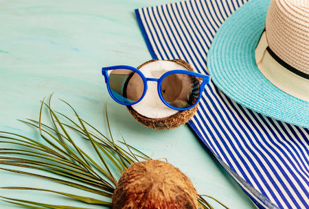 Summer composition or layout. Tropical palm leaves, hat, glasses, beach towel, coconut on a...