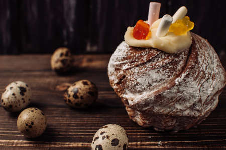Stylish Easter cake with marshmallows and jelly bears on dark rustic wooden background,quail eggs lie nearby.Seasonal Greetings Happy Easter. place for text. Selective focus. modern happy easter imageの写真素材