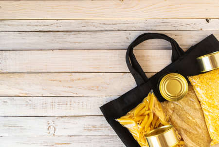 fabric bag zero waste with food supplies quarantine food crisis isolated on a wooden white background. Rice, pasta, canned food, corn plastics, toilet paper. Food Delivery, Donation Concept.Copyspaceの写真素材