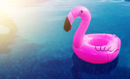 A little inflatable flamingo swims in a pool in the sunlight. Coasters for the pool. The concept of summer pastime. Beach summer compositionの写真素材