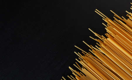 yellow raw homemade spaghetti paste on a black concrete background in the right corner. Top view. The concept of cooking and diet. Copy space.の写真素材