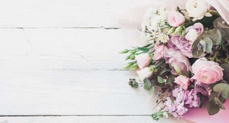 a large and beautiful bouquet of fresh roses, eustoma, matiola, freesia, eucalyptus, hydrangea in delicate pink and white colors, on a white wooden background in the style of Provence. Copy space.の写真素材