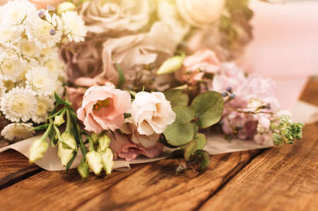 a large and beautiful bouquet of fresh roses, eustoma, matiola, freesia, eucalyptus, hydrangea in delicate pink and white colors, on a brown wooden background in rustic style.の写真素材
