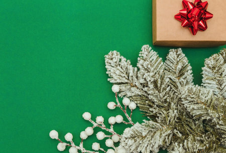Christmas or New Year composition. Craft gift box with red bow and Christmas decorations on green...