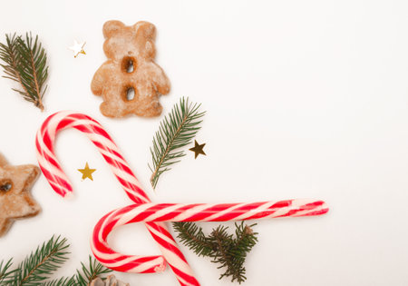 Christmas flat composition of fir branches, candies, gingerbread and sparkles with copy space for text. Top view on a white background. Layout.の写真素材