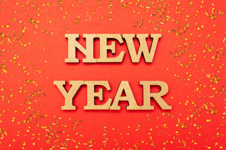 Happy new year celebration. Wooden letters in a New Year's cap on a red background with candy....