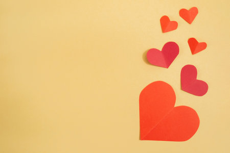 Valentines Day background. Pink and red hearts on a pastel yellow background. Valentines Day concept. Flat lay, top view, copy spaceの写真素材