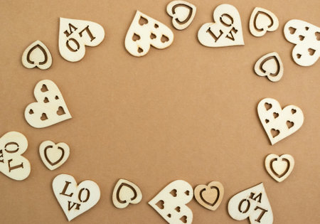 Wooden hearts on a pastel craft paper background in the form of a frame. Abstract background with wood cut shapes. Sainte Valentine. Copy space.の写真素材