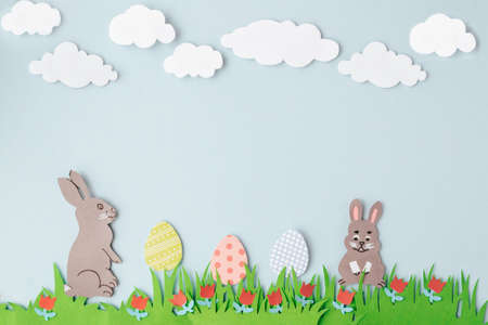 Happy Easter Handmade greeting card with paper rabbits, decorated eggs, green grass and tulips. Space for text. Top view with copy space. Vertical orientation.の写真素材