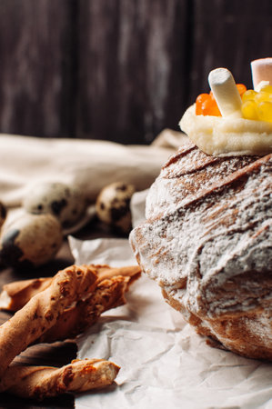 Stylish Easter cake with marshmallows and jelly bears on parchment paper on a rustic wooden background. Seasonal greetings of happy Easter. selective focus. modern happy easter imageの写真素材