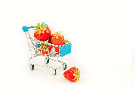 Basket with fresh strawberries isolated on white. Sweet organic flavored strawberries in a mini shopping trolley. Concept of fresh fruits and berries online on the internet.の写真素材