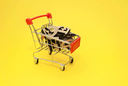 wooden letters of the English alphabet lie in a miniature shopping trolley on a yellow background, close-up.Knowledge buying concept. Copy space.の写真素材
