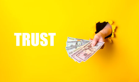 A hand holding a stack of money with the word trust written below it. Concept of financial security...