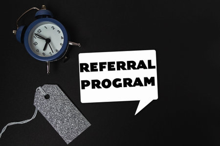 A clock is on a table with a tag that says referral program