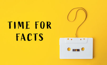 A white cassette tape is hanging from a string with the words Time for Facts written below itの写真素材