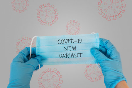 A blue mask with the word variant written on it. The mask is being held by a person in a blue gloveの写真素材