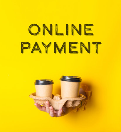 A person holding two cups with the words online payment written above them. The image has a bright yellow background and a playful, fun vibeの写真素材