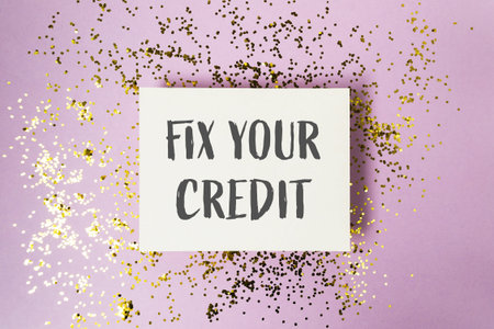 A white sign with the words Fix Your Credit written on it. The sign is placed on top of a purple...