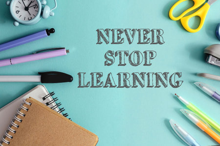 Never stop learning is the message on this image. A variety of school supplies, including pens, scissors, and a clock. The supplies are arranged in a way that emphasizes the importance of educationの写真素材