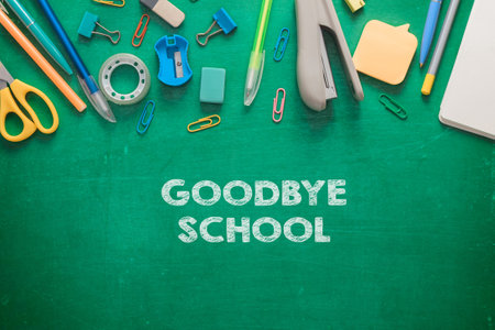 A green chalkboard with a variety of school supplies and the words Goodbye School written on itの写真素材