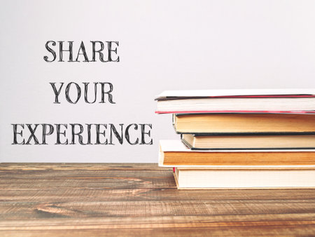 A stack of books with the words share your experience written on top. Concept of sharing one's experiences and knowledge with others. Scene is positive and encouragingの写真素材