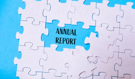 A jigsaw puzzle with a piece missing and the word Annual Report written in the gap. The puzzle is on a blue backgroundの写真素材