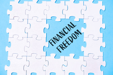 A jigsaw puzzle with the word financial freedom written in the middle. The puzzle pieces are scattered around the word, creating a sense of disarray and confusionの写真素材