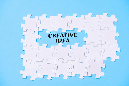 A puzzle with the word creative idea written in the middle. The puzzle is made up of white pieces...