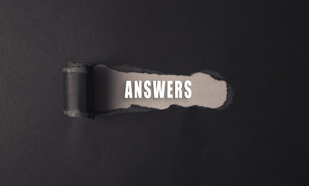A black and white image of a torn piece of paper with the word answers written on it. Concept of...