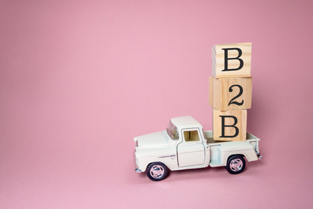 A white truck is carrying a stack of wooden blocks. The blocks spell out the word B2B on the truck. Concept of business and productivityの写真素材