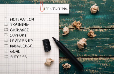 A piece of paper with a list of words and a pen on it. The words on the paper are motivation, training, guidance, support, leadership, knowledge, goal, and successの写真素材