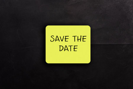 Save the date sticker on a black background. The sticker is yellow and has the word save on itの写真素材
