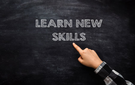 A hand pointing to the word learn new skills on a blackboard. Concept of continuous learning and personal growthの写真素材