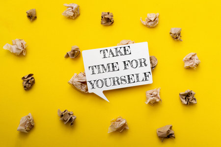 A yellow background with a white sign that says Take time for yourself. There are also many pieces of paper scattered around the sign, creating a messy and chaotic appearanceの写真素材
