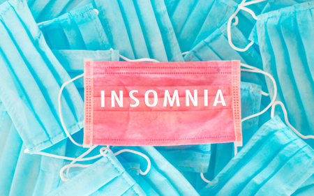 Pile of blue and pink masks with the word Insomnia written on them. Concept of chaos and disorder, as the masks are scattered and piled on top of each otherの写真素材